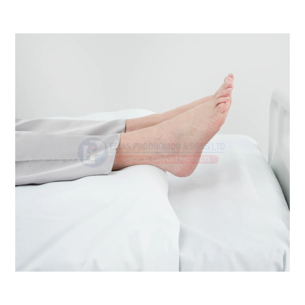 Standard Wedge positioning beneath bed linen, heels beyond the edge. Bed and linen shown for context are not included.